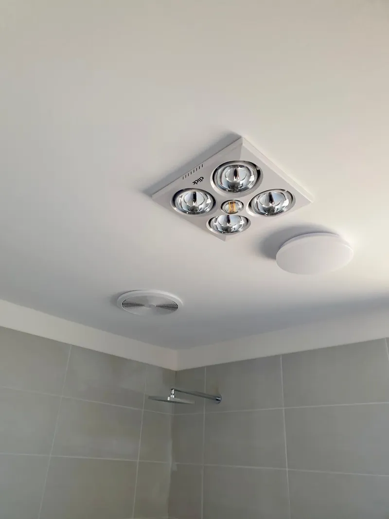 Bathroom ceiling with a four-lamp heat and exhaust unit beside a round ceiling light