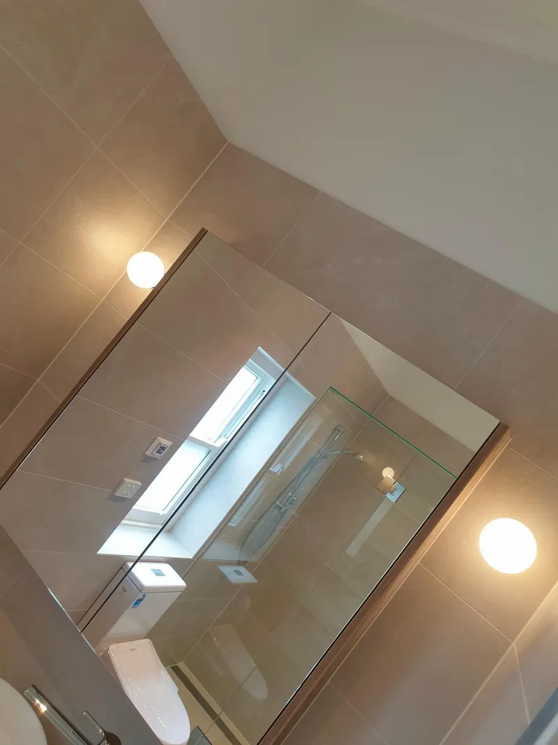 Bathroom with round wall lights either side of a mirror cabinet on a tiled wall