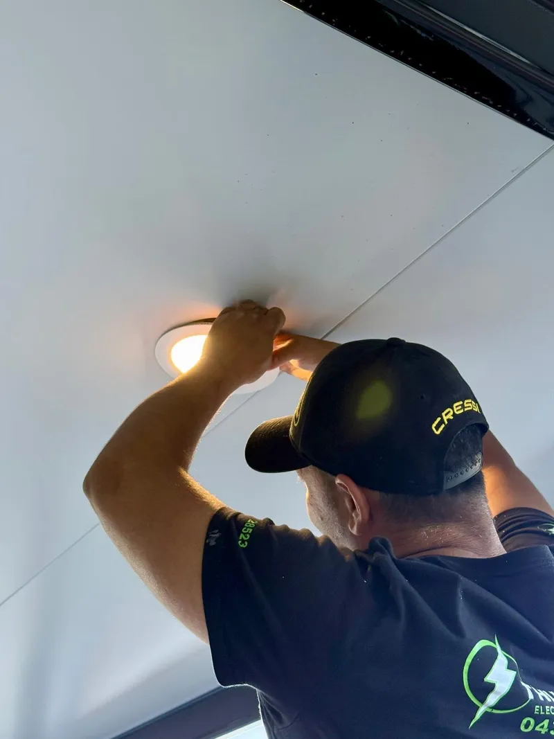 Yiannis fitting a downlight into a white ceiling