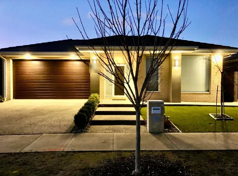 Single-storey home at dusk with the garage and front façade lights switched on