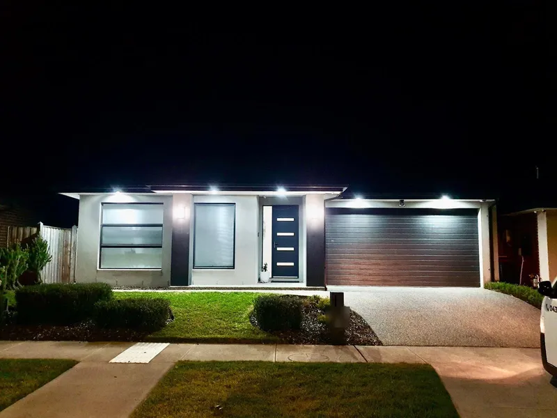 Single-storey home at night with façade lights and the entry light on
