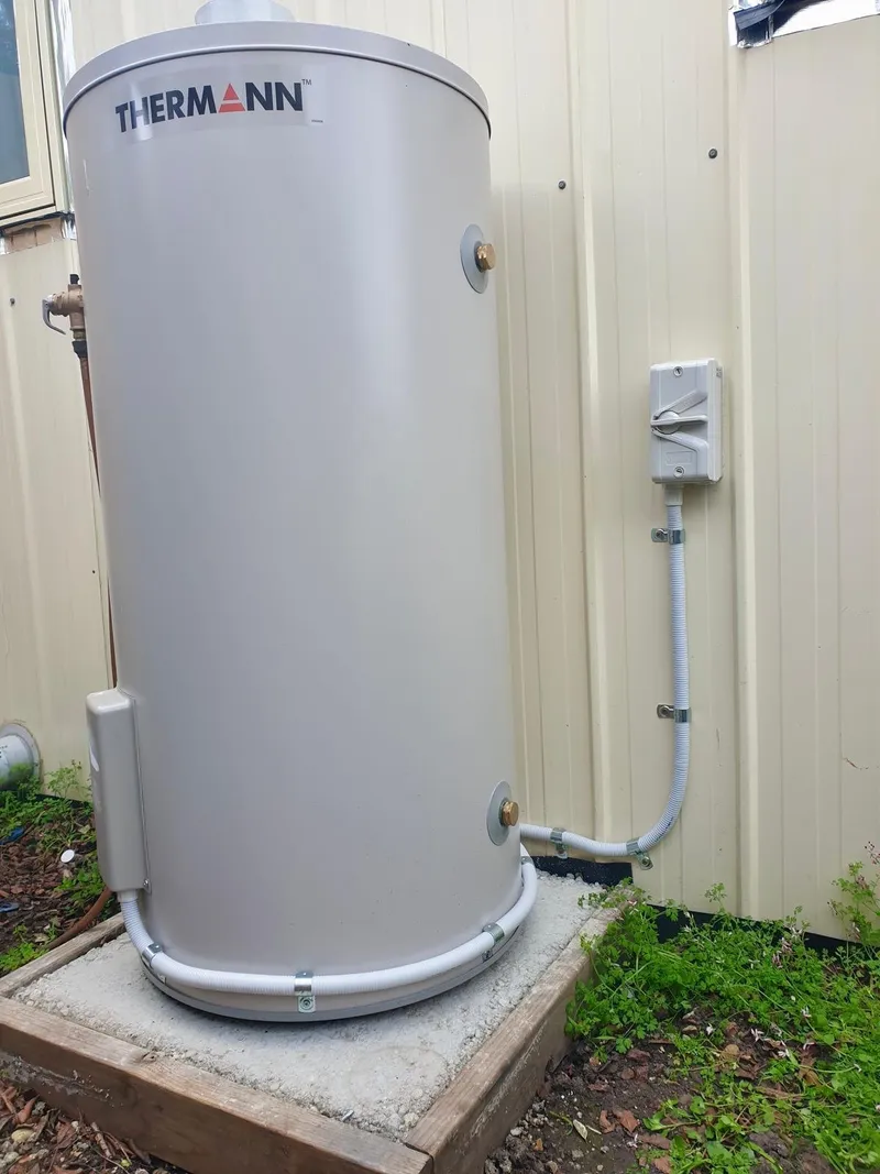 Thermann hot water unit on a concrete pad, wired to an isolator switch on the wall