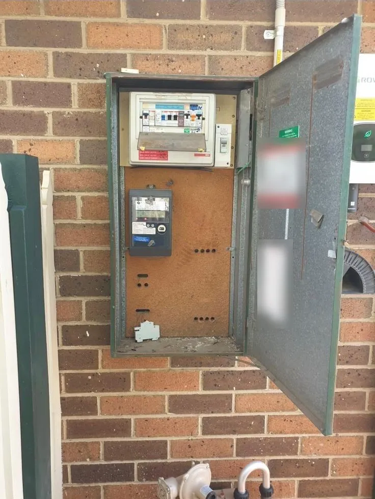 Before: an older green meter box on a brick wall, with a small switchboard and meter on a worn backing panel
