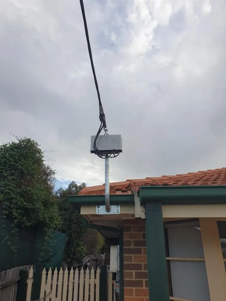 After: the overhead power line connected to a new galvanised mast bolted under the eave of the same home