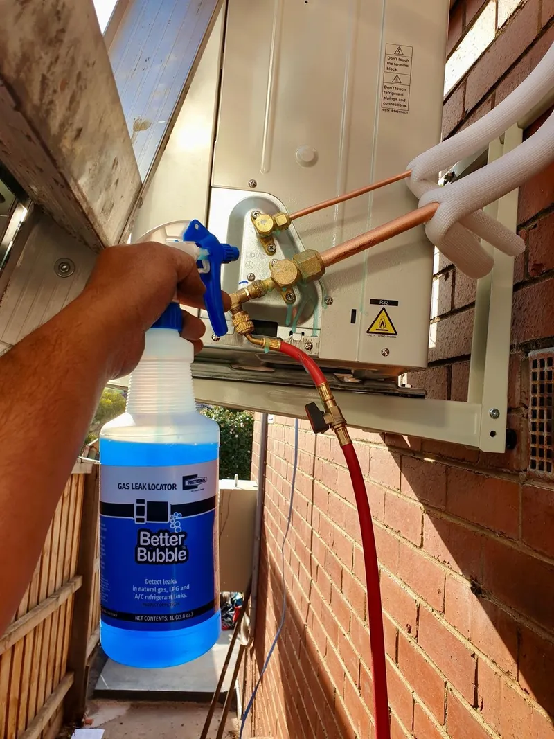 Leak-detection spray being applied to the pipe connections of an outdoor unit
