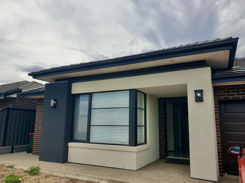 Front of a new single-storey home with an exterior wall light beside the entry