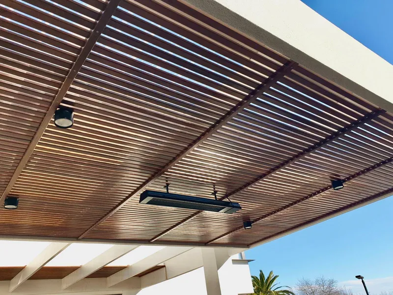 Timber-slat pergola fitted with an outdoor strip heater and small downlights