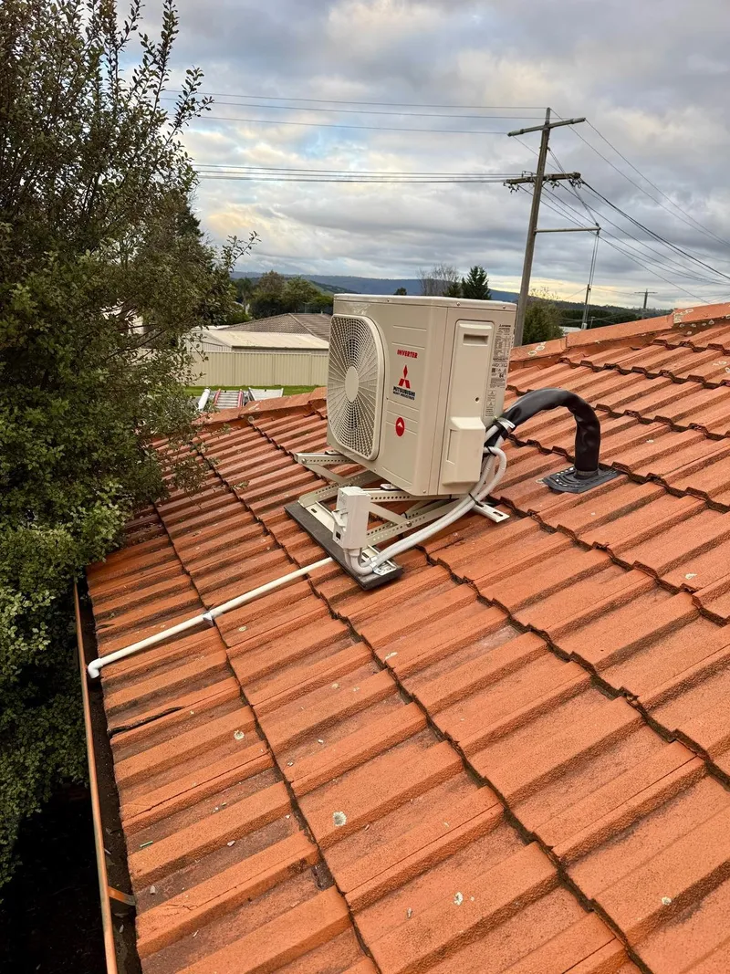 Mitsubishi outdoor unit on a roof-mount frame on a terracotta tiled roof