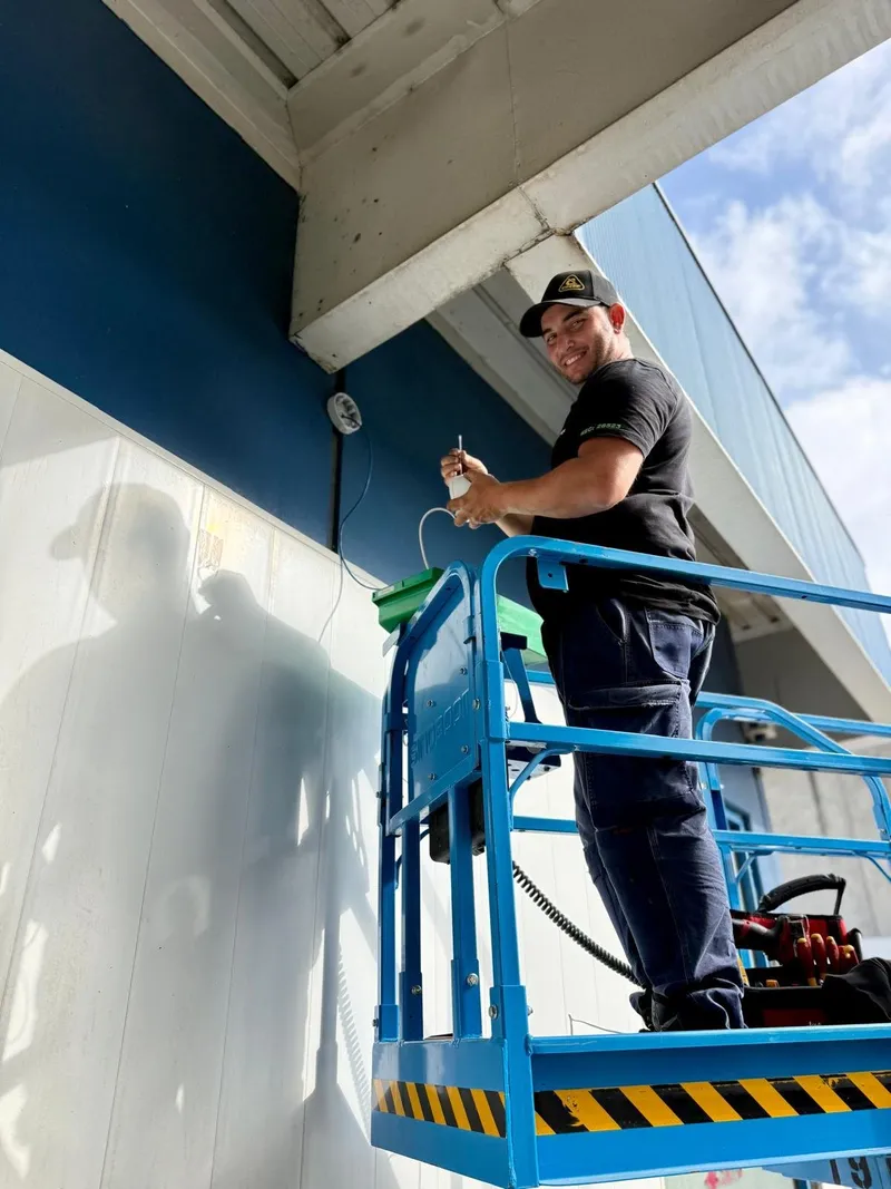 Yiannis on a scissor lift fitting a small device to the underside of a building eave
