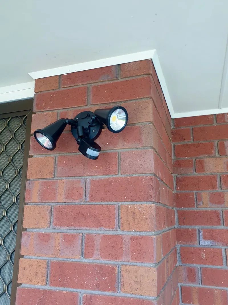 Twin LED sensor floodlight on the corner of a red brick wall