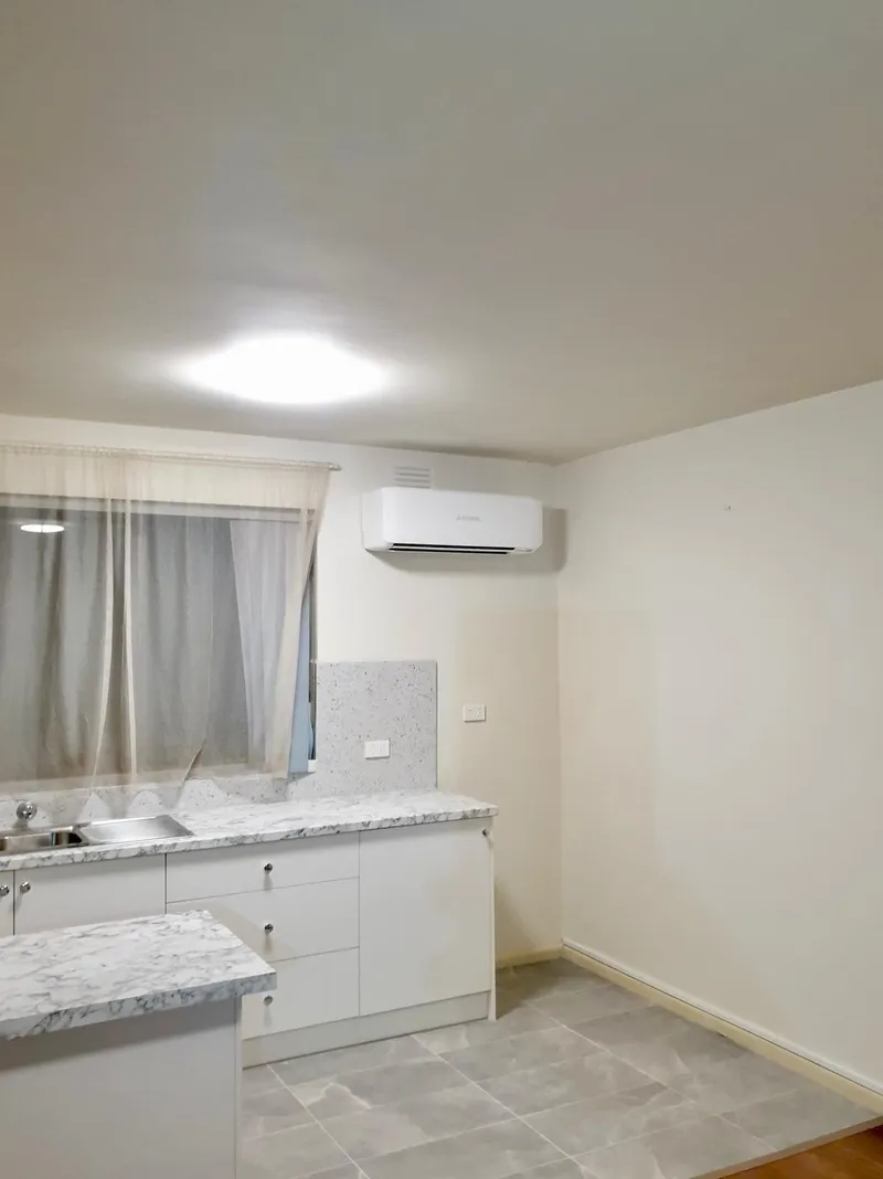 Split system mounted above a renovated kitchenette with stone benchtops