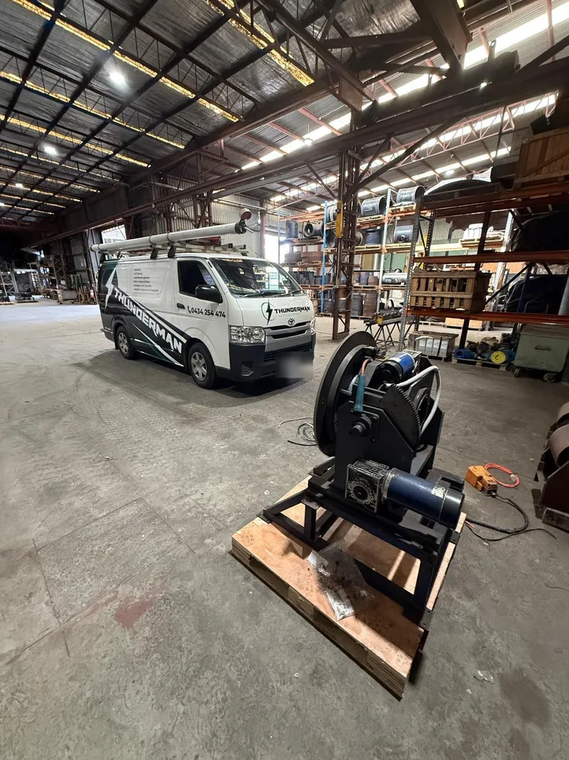 Thunderman van parked in a large industrial shed beside a motor and gearbox assembly on a pallet
