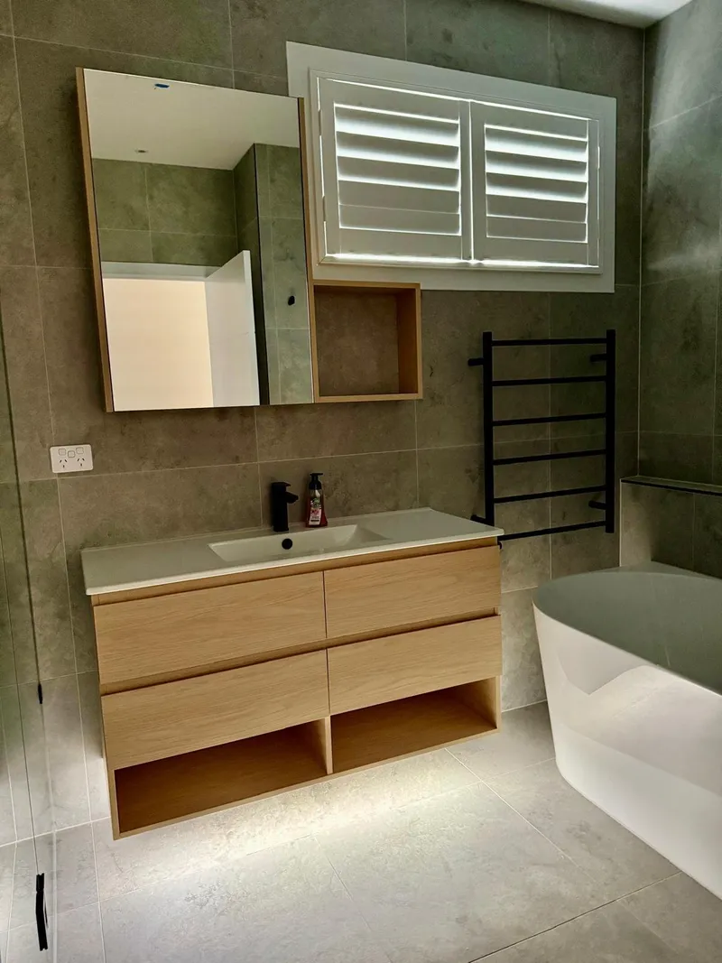 Bathroom vanity with LED strip lighting underneath, a black heated towel rail and a freestanding bath