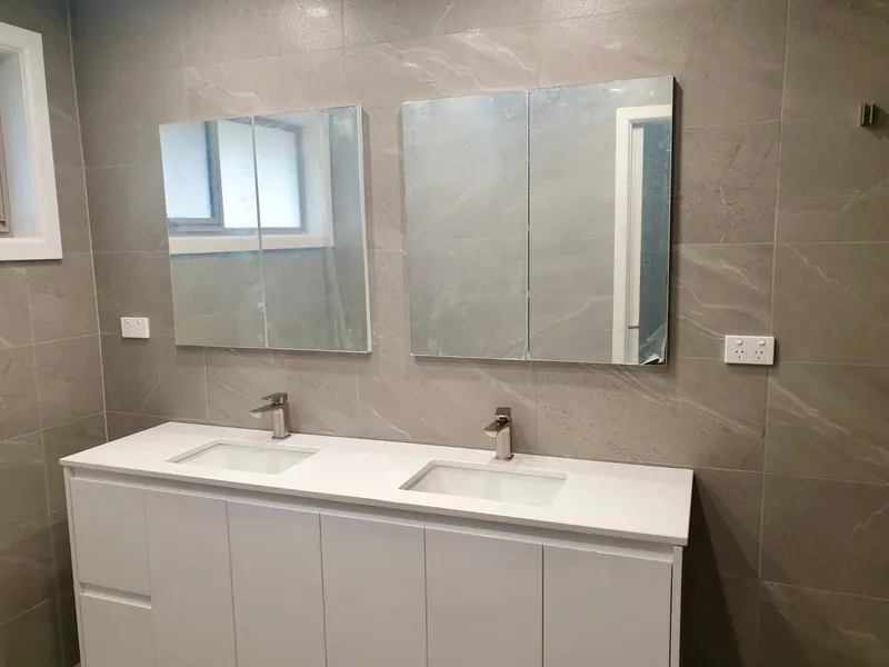 Bathroom vanity with two basins and mirror cabinets, with power points on the tiled wall