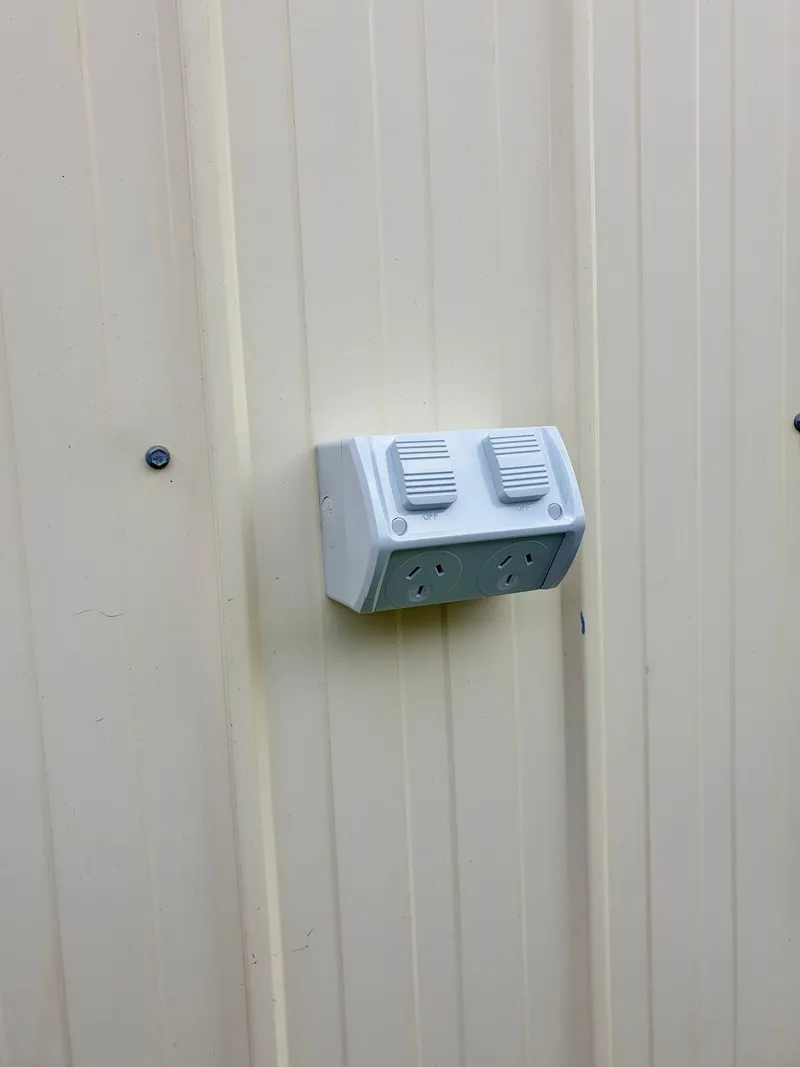 Weatherproof double power point on a cream steel wall