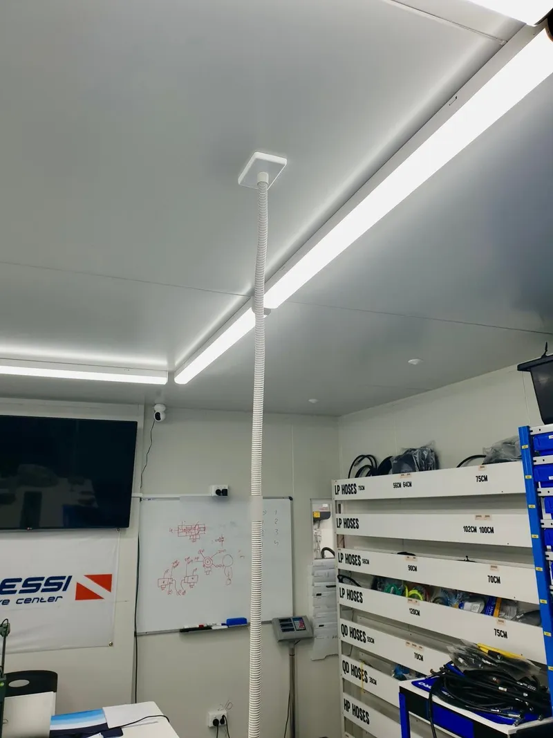 Workshop ceiling fitted with long LED batten lights above shelving of labelled hoses