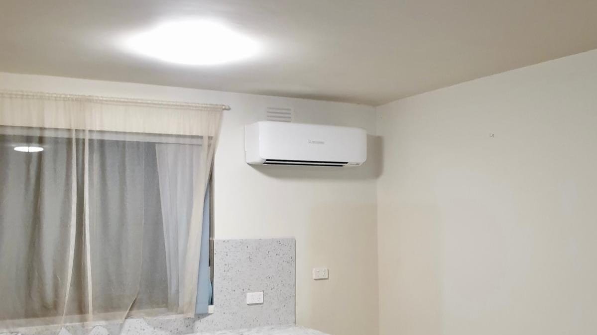Split system above a kitchenette with stone benchtops and a window