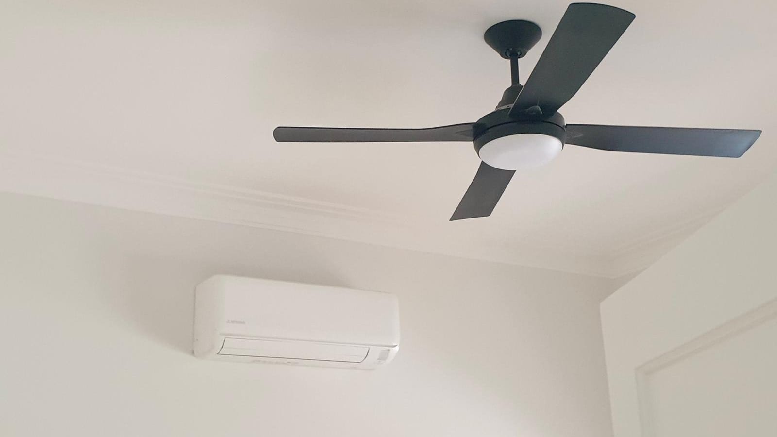 Black ceiling fan with a light above a wall-mounted split system