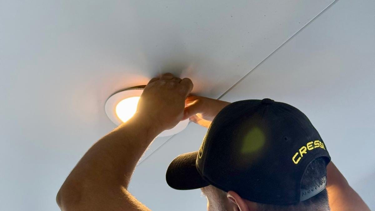 Yiannis fitting a downlight into a white ceiling