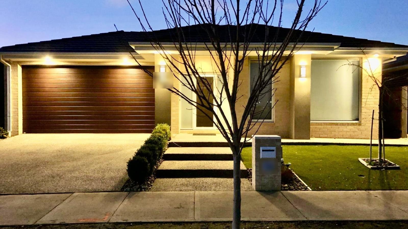 Single-storey home at dusk with the garage and façade lights on