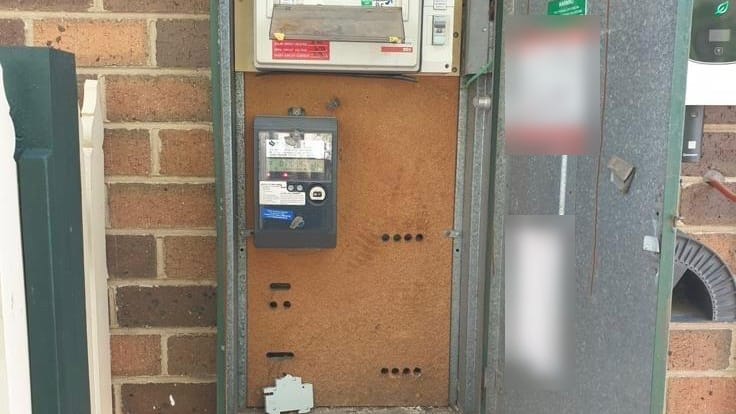 Older green meter box with a small switchboard and meter on a worn backing panel