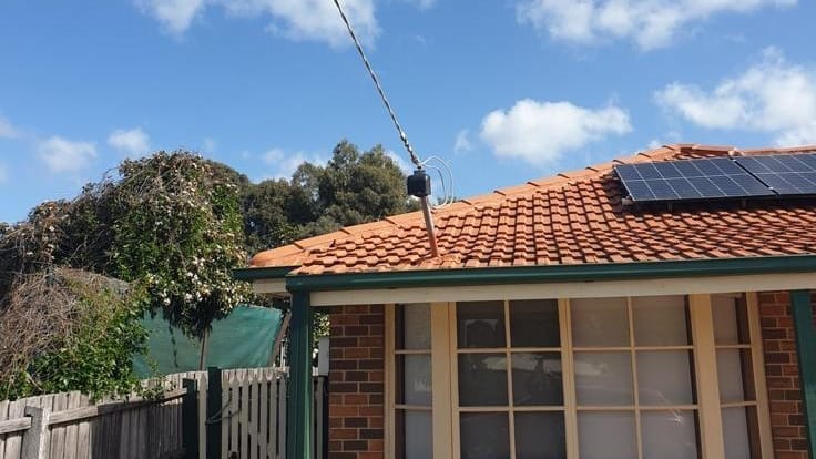 Overhead power line running to the roof edge of a brick home with solar panels
