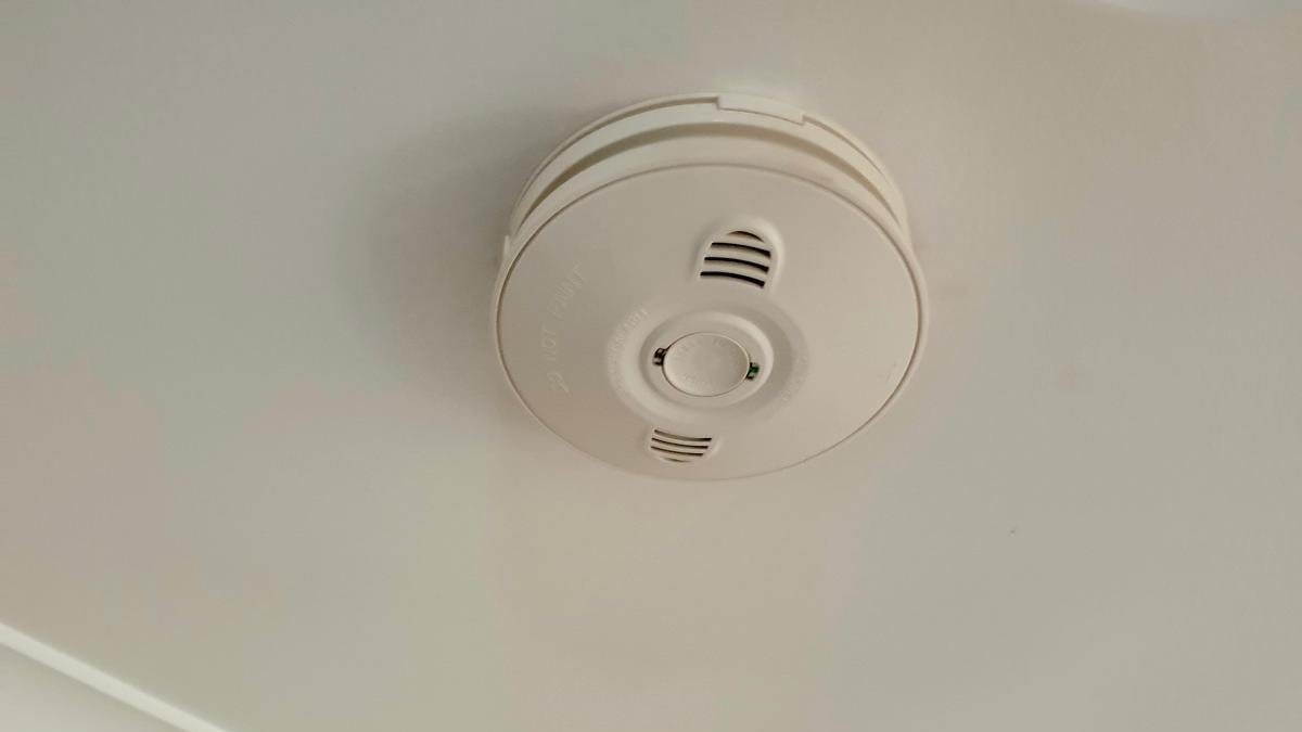 Smoke alarm fitted to a ceiling near the cornice