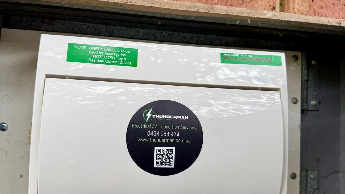 Switchboard cover with green notice labels and a Thunderman sticker