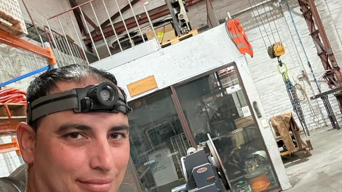 Yiannis wearing a head torch inside a large industrial workshop