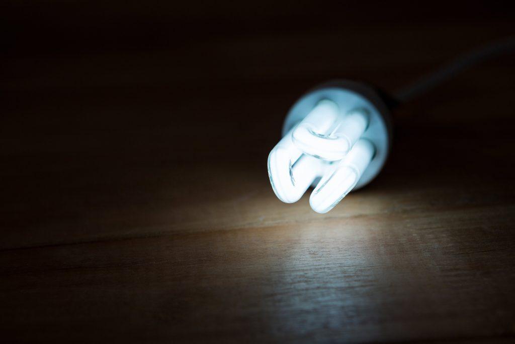 Energy-efficient light bulb glowing on wooden surface